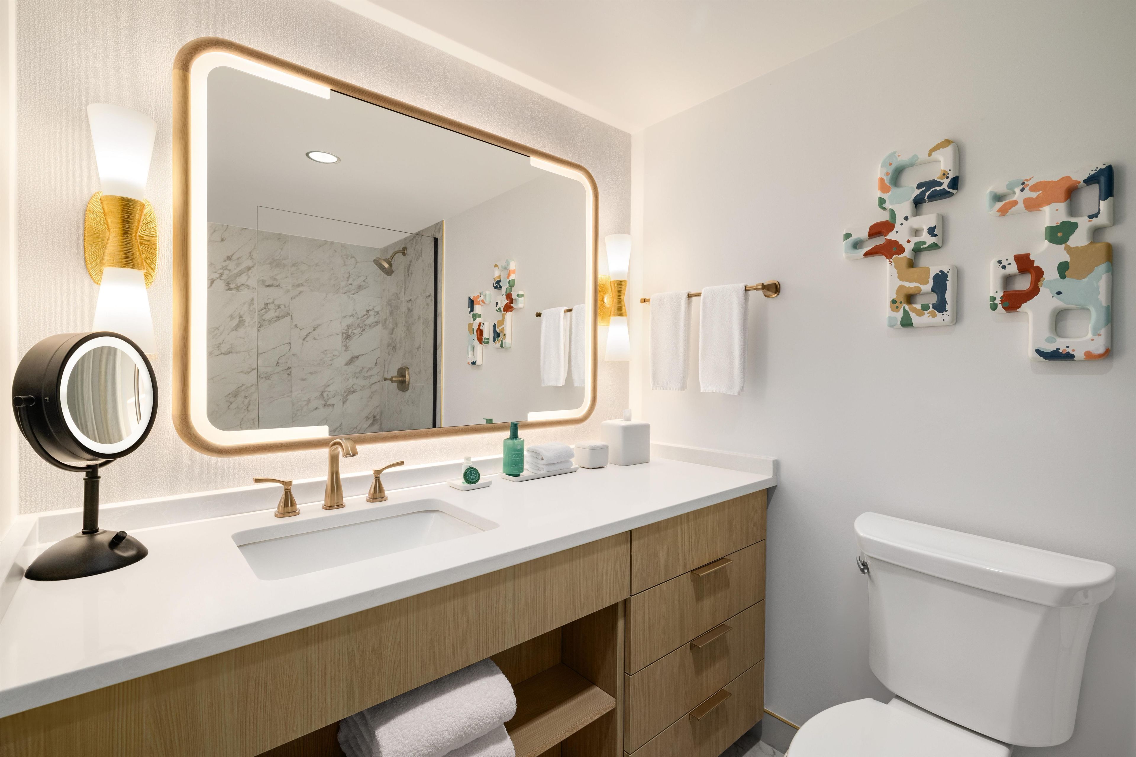 Een moderne badkamer met een grote spiegel, een wastafel en een toilet.
