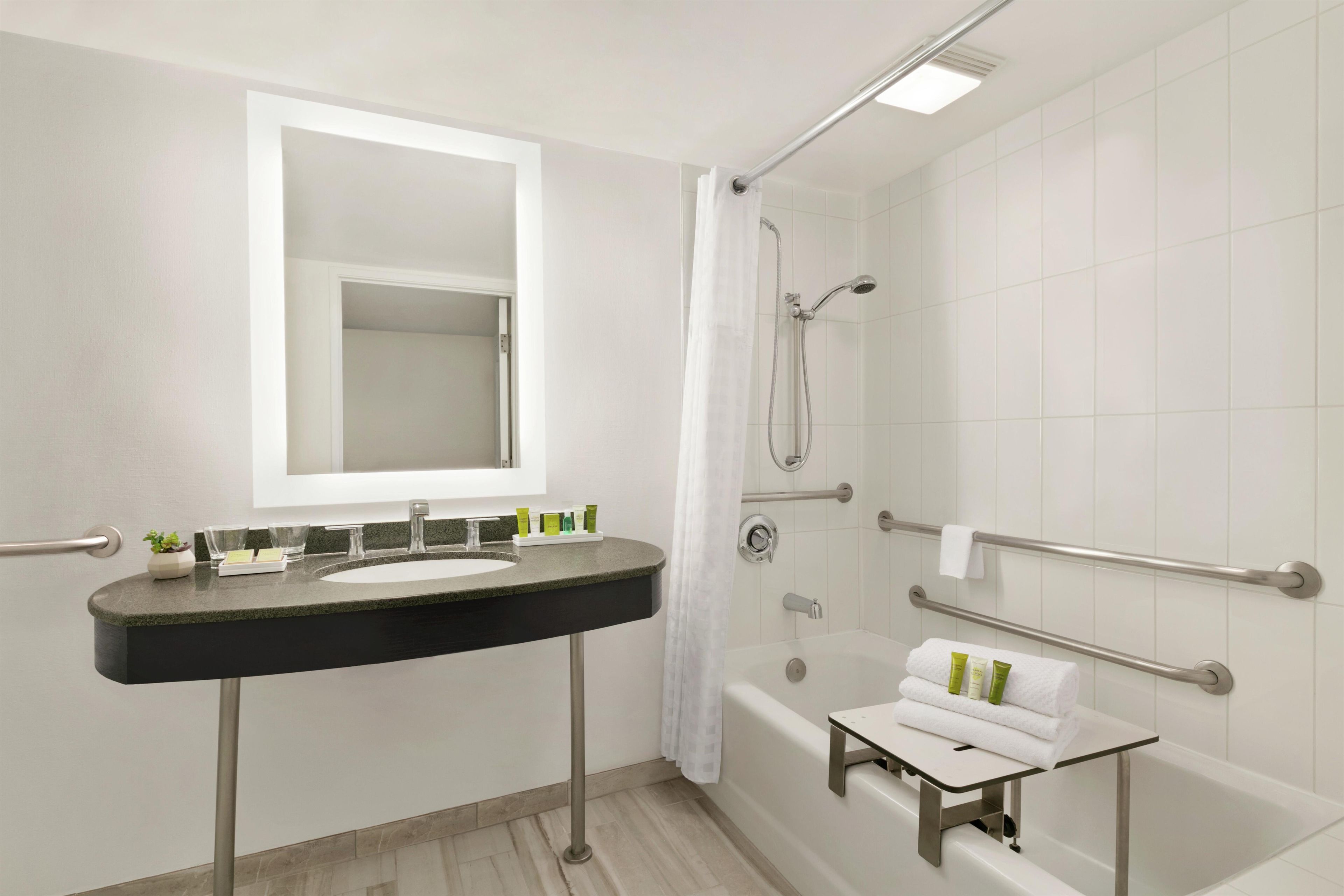 Een moderne badkamer met een wastafel, spiegel, douche en bad.