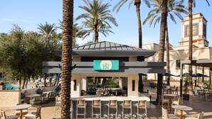 A bar area with outdoor seating, palm trees, and a pool in the background. - Hilton Scottsdale Resort & Villas (Scottsdale)