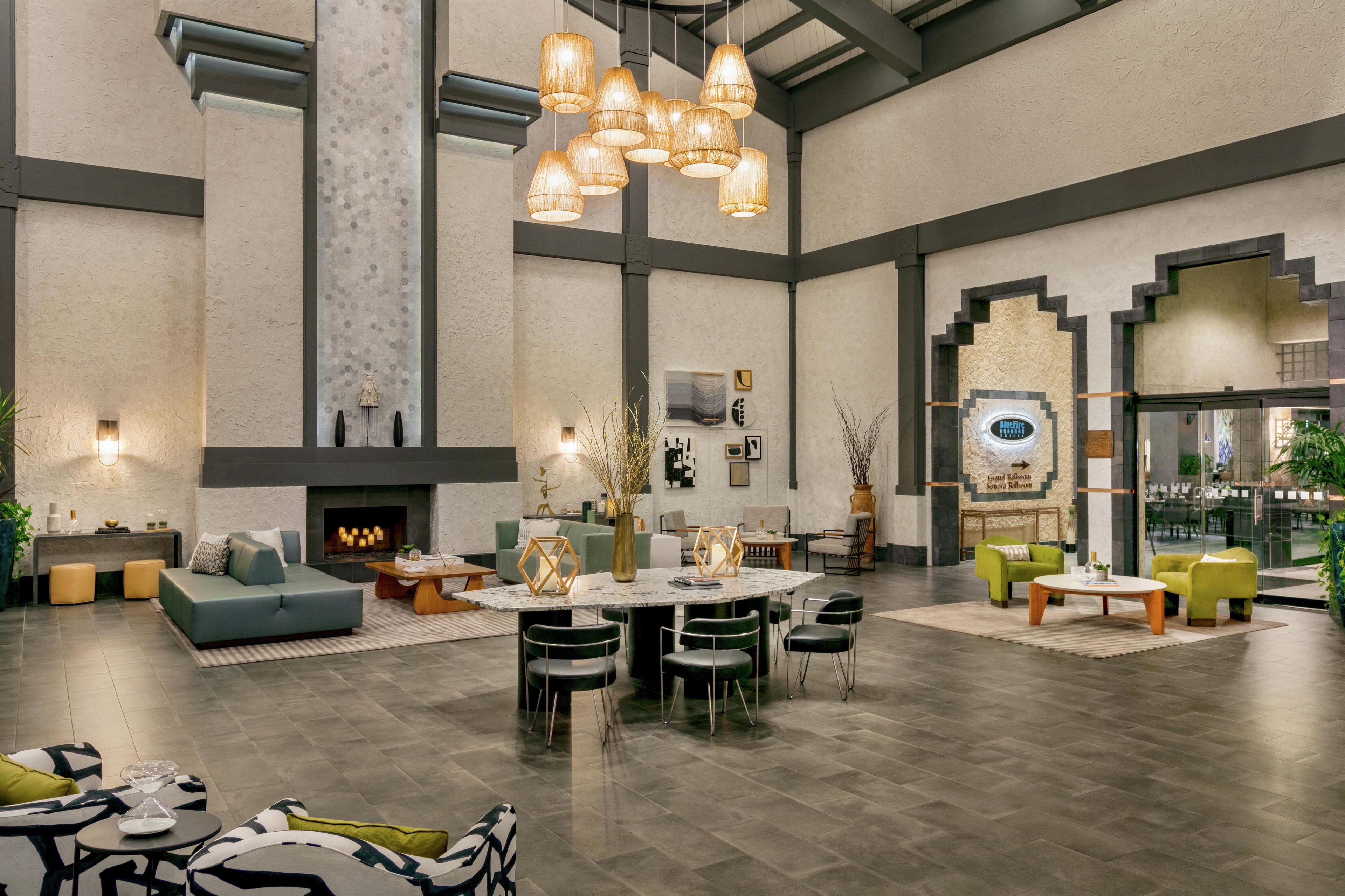A spacious living area with a fireplace, a round dining table surrounded by chairs, and a seating area with sofas and armchairs.