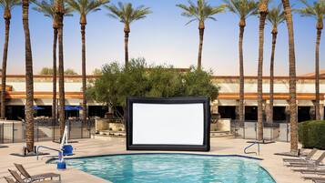 Relax by the serene pool surrounded by palm trees and lounge chairs.