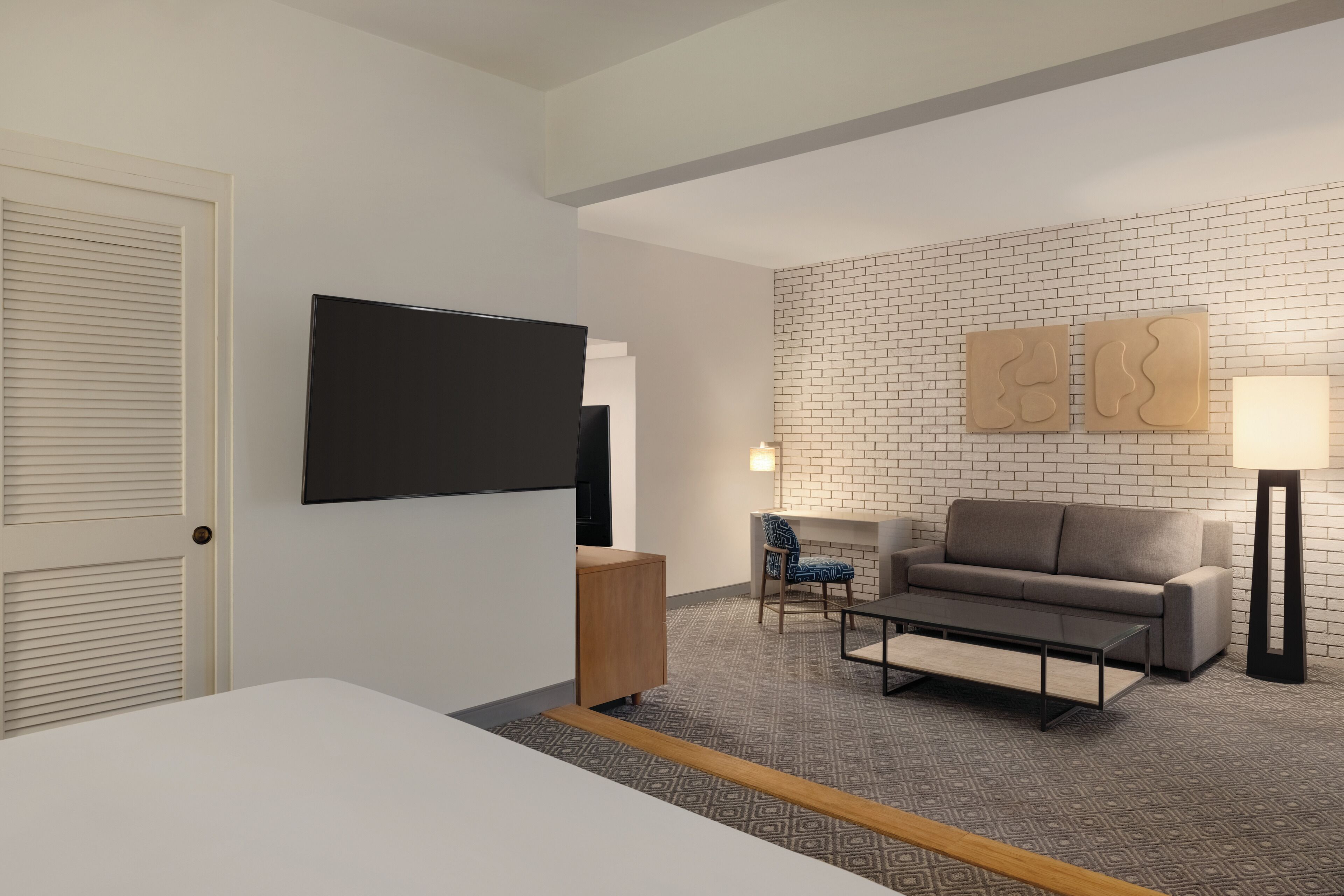 Une chambre d’hôtel moderne équipée d’une télévision à écran plat, d’un canapé, d’une table basse et d’une cheminée.