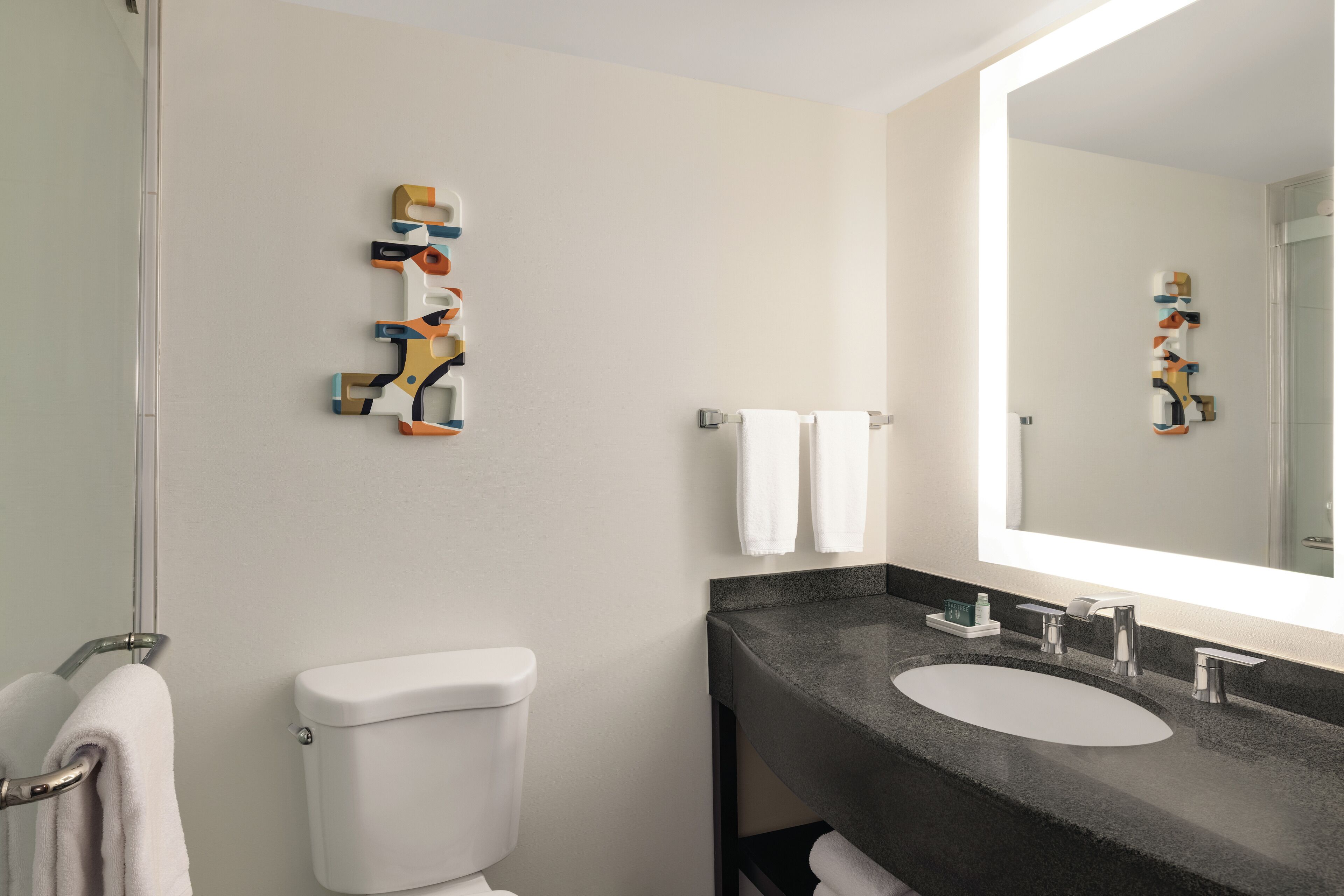 Un baño moderno con inodoro, lavamanos y espejo.