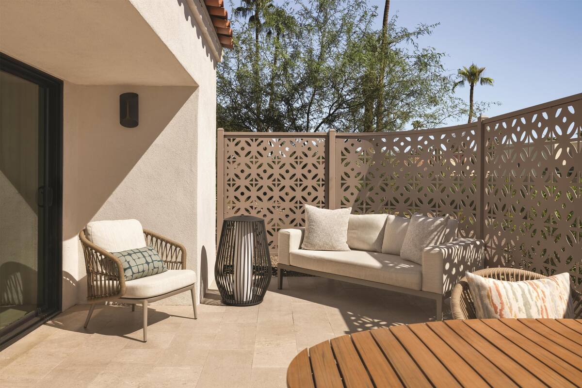A patio with a sofa, chairs, and a table.