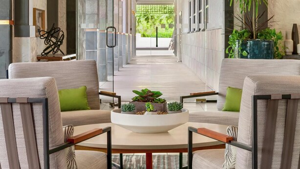 A modern interior with a central seating area, a staircase leading to an outdoor area, and a view of greenery. - Hilton Scottsdale Resort & Villas (Scottsdale)