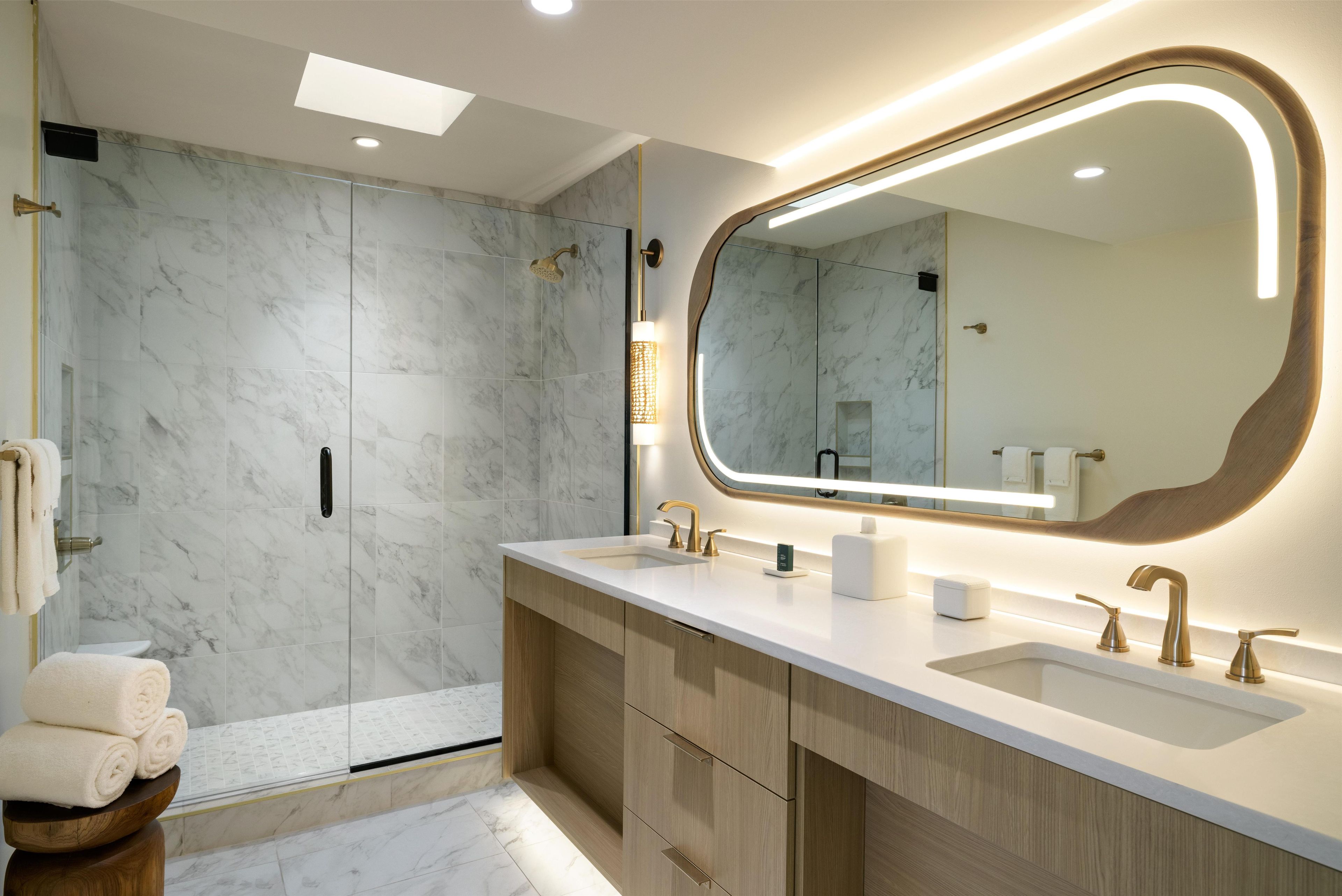 A modern bathroom with a large mirror, dual sinks, and a shower area.