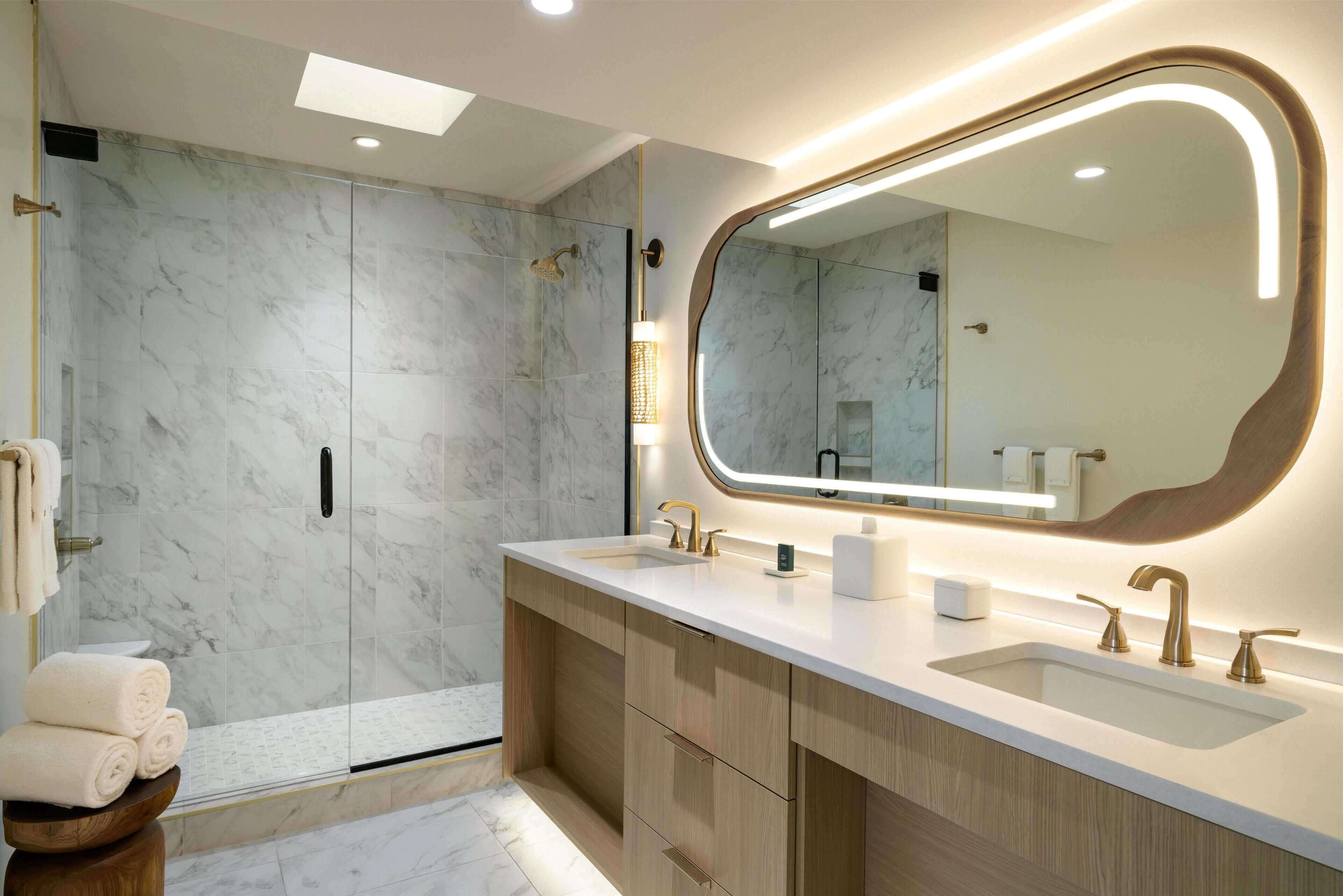 Une salle de bain moderne dotée d’un grand miroir, de deux vasques et d’un espace douche.
