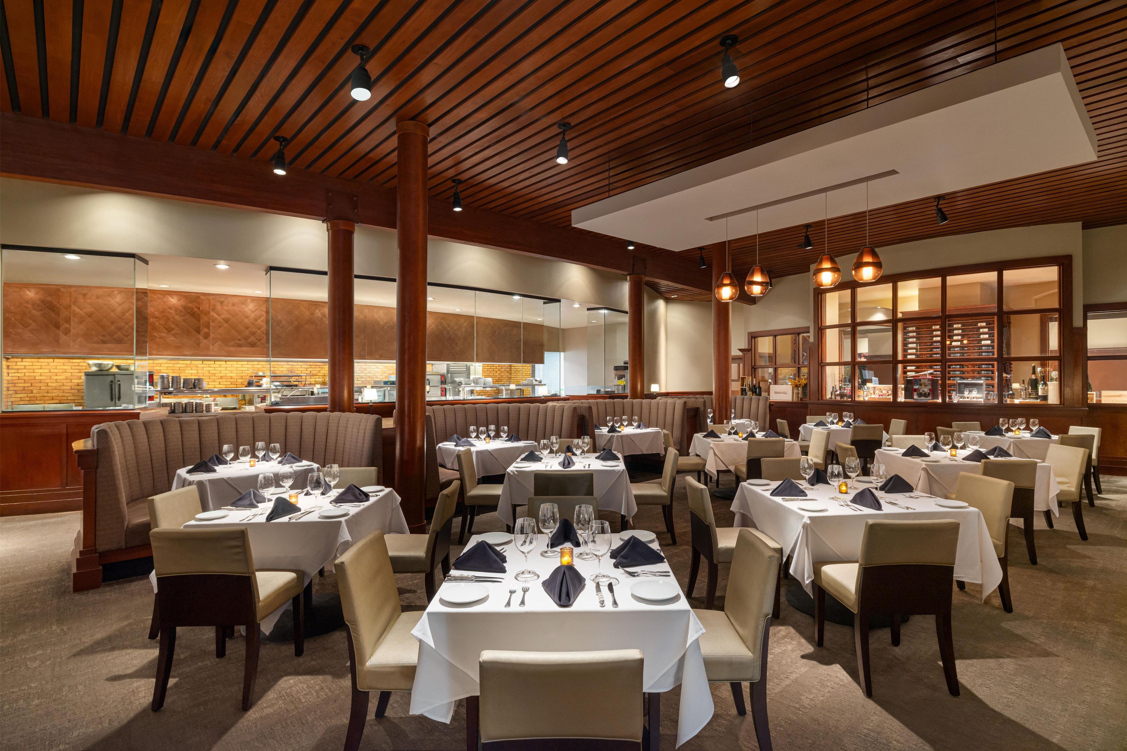 A restaurant with multiple dining tables, booths, and a kitchen visible in the background.