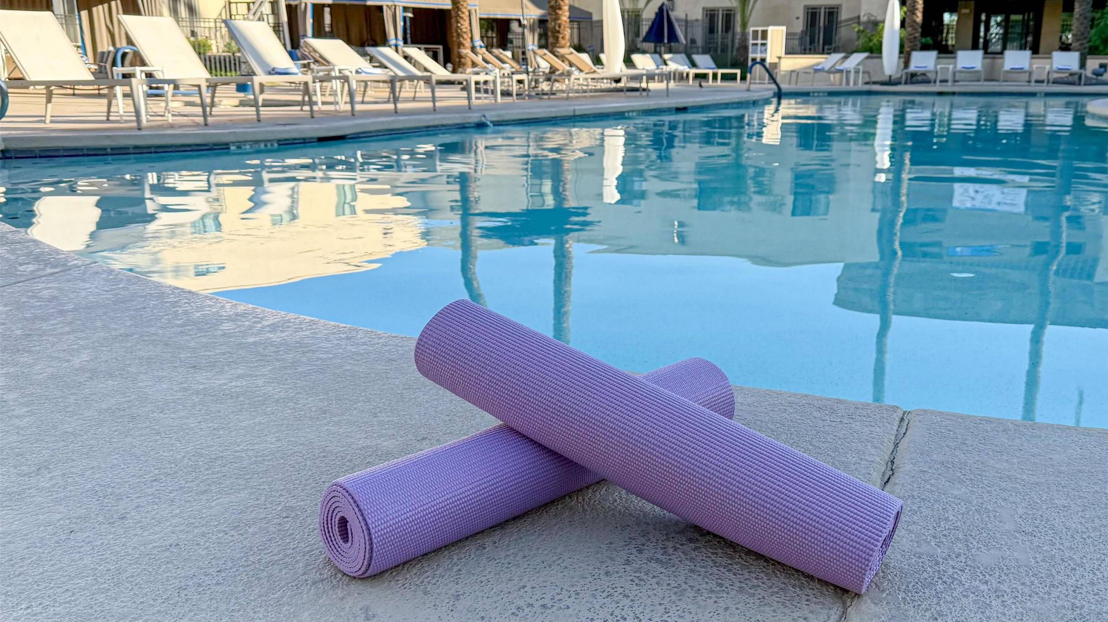 Un espace aménagé au bord de la piscine, avec un tapis de yoga et des chaises longues.
