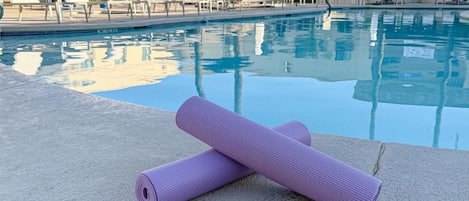 Un espace aménagé au bord de la piscine, avec un tapis de yoga et des chaises longues.