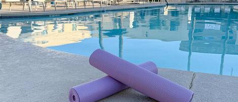 Un espace aménagé au bord de la piscine, avec un tapis de yoga et des chaises longues.
