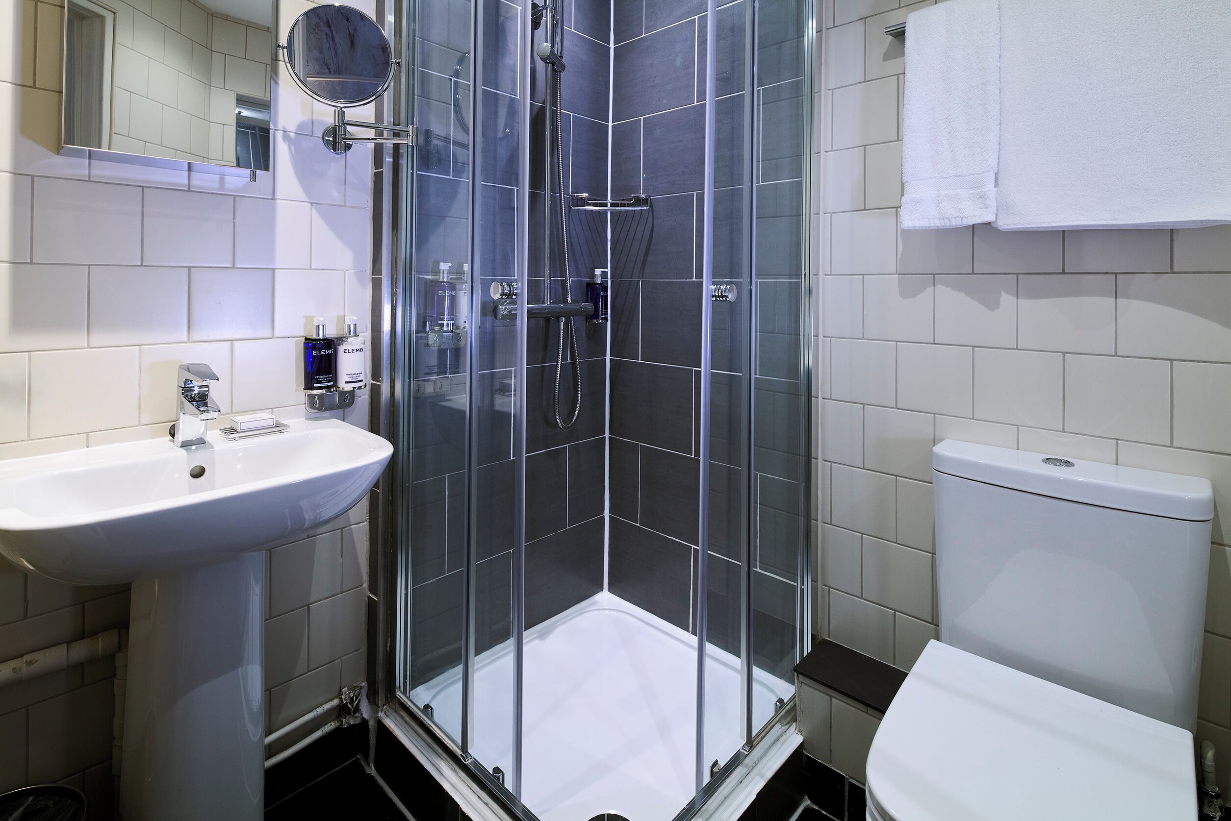 A modern bathroom with a glass-enclosed shower, a white sink, and a toilet.