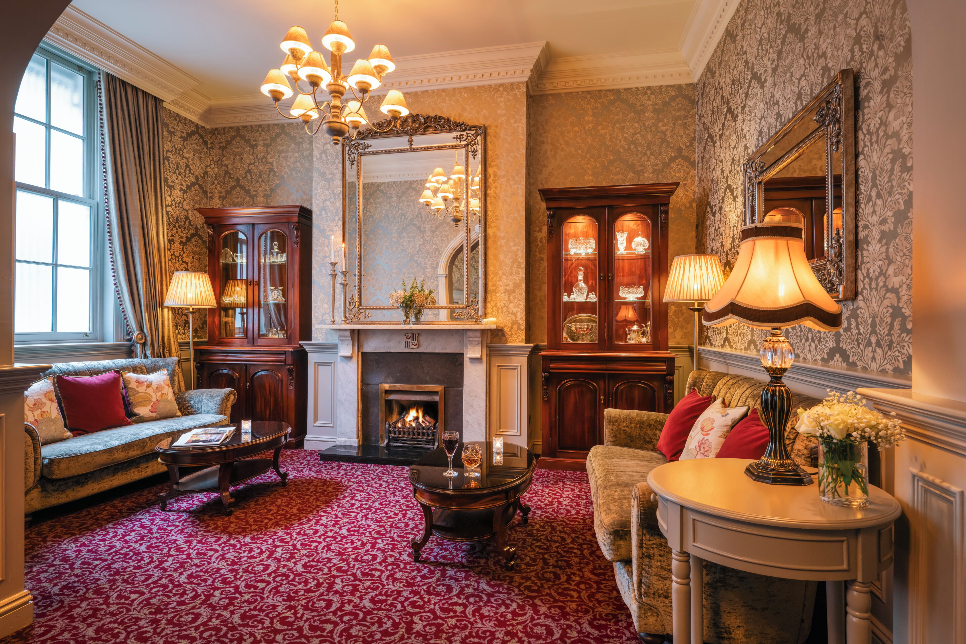 A traditional room with a fireplace, seating, and a large mirror.
