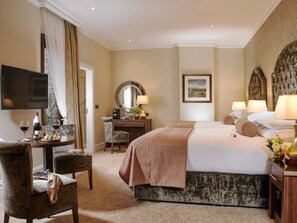 Habitación de hotel con cama, escritorio con silla, televisor y mesa de comedor con sillas.