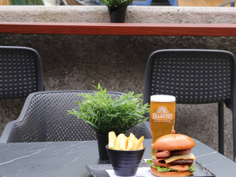 Una mesa con una hamburguesa, papas fritas y un vaso de cerveza.