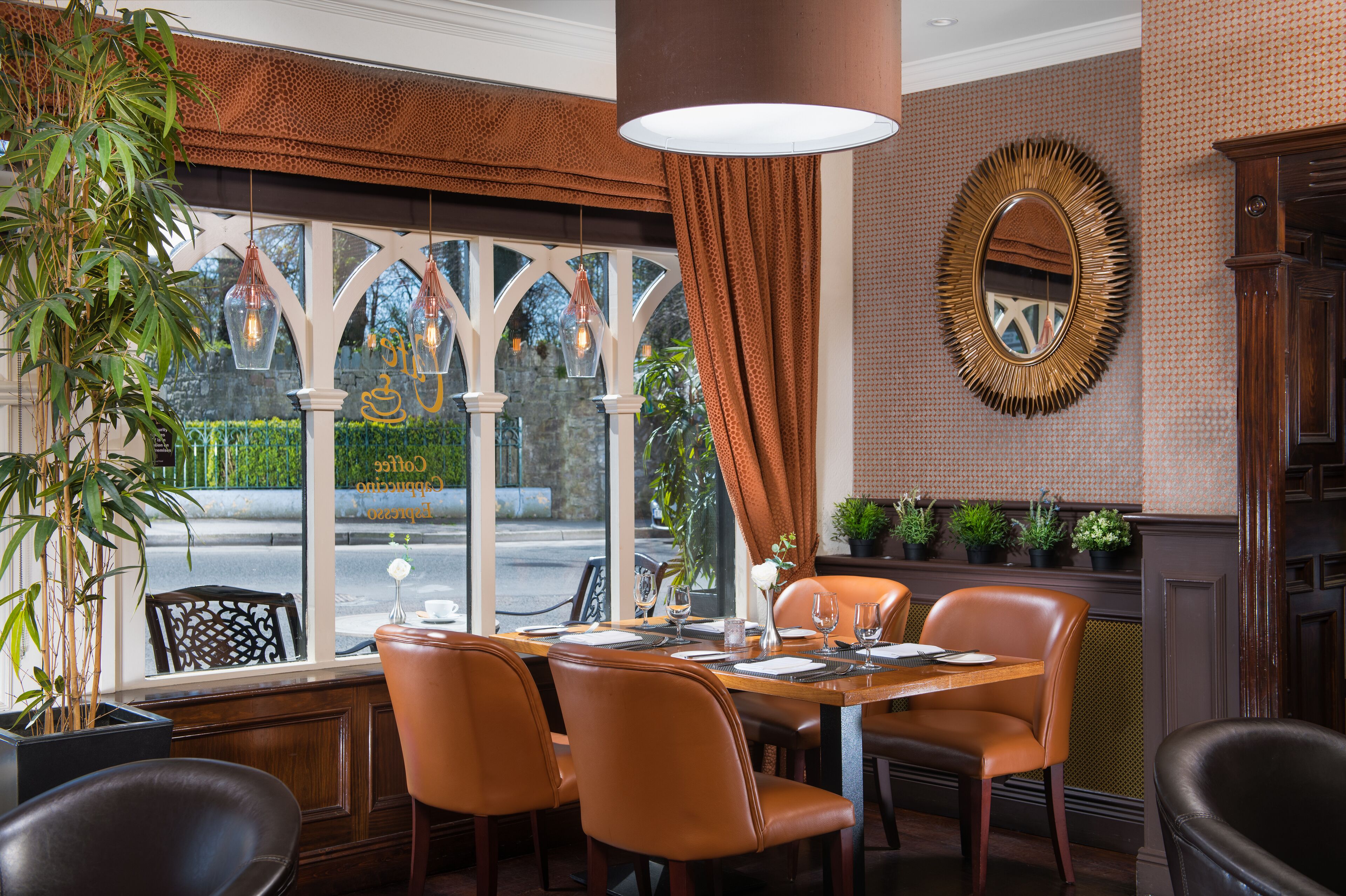 A restaurant with a table set for four, a large window with a view of the street, and a mirror on the wall.