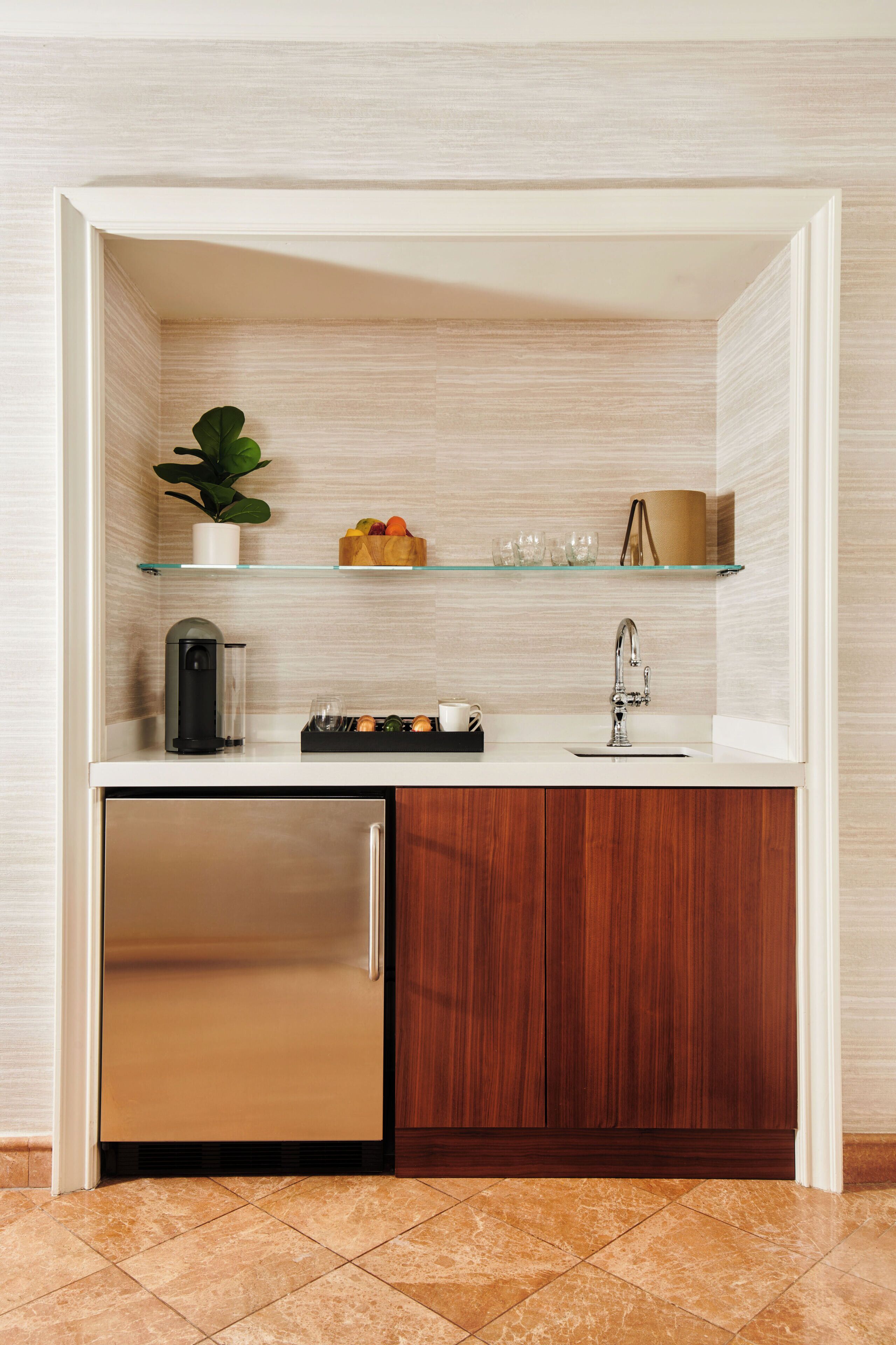 A compact kitchen with a built-in refrigerator, a coffee machine, and a sink.