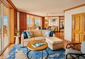 A spacious living room with a large sectional sofa, a round coffee table, and a view of the balcony.
