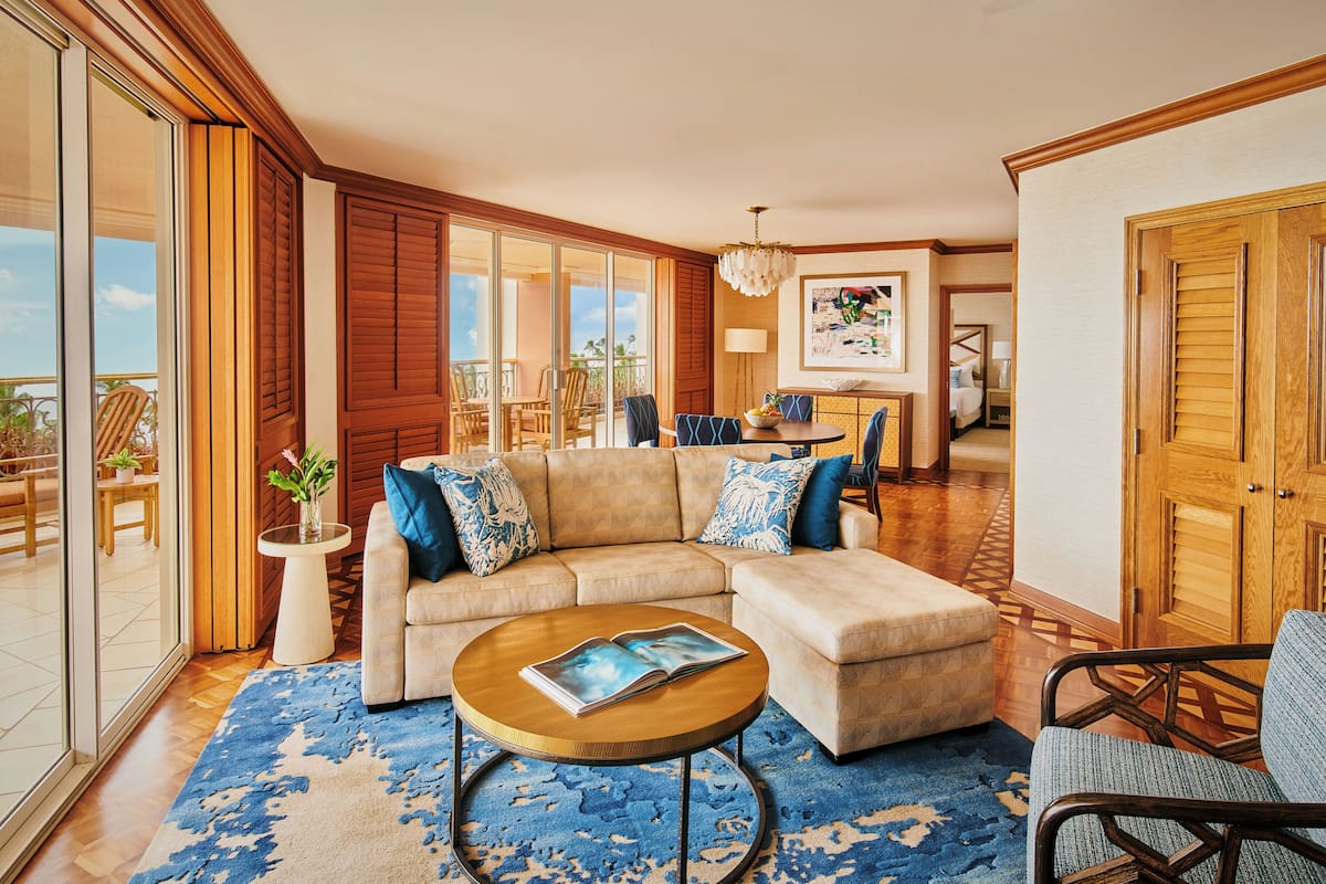 A spacious living room with a large sectional sofa, a round coffee table, and a view of the balcony.