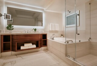 A modern bathroom with a large mirror, a glass-enclosed shower, and a wooden vanity with built-in shelves.