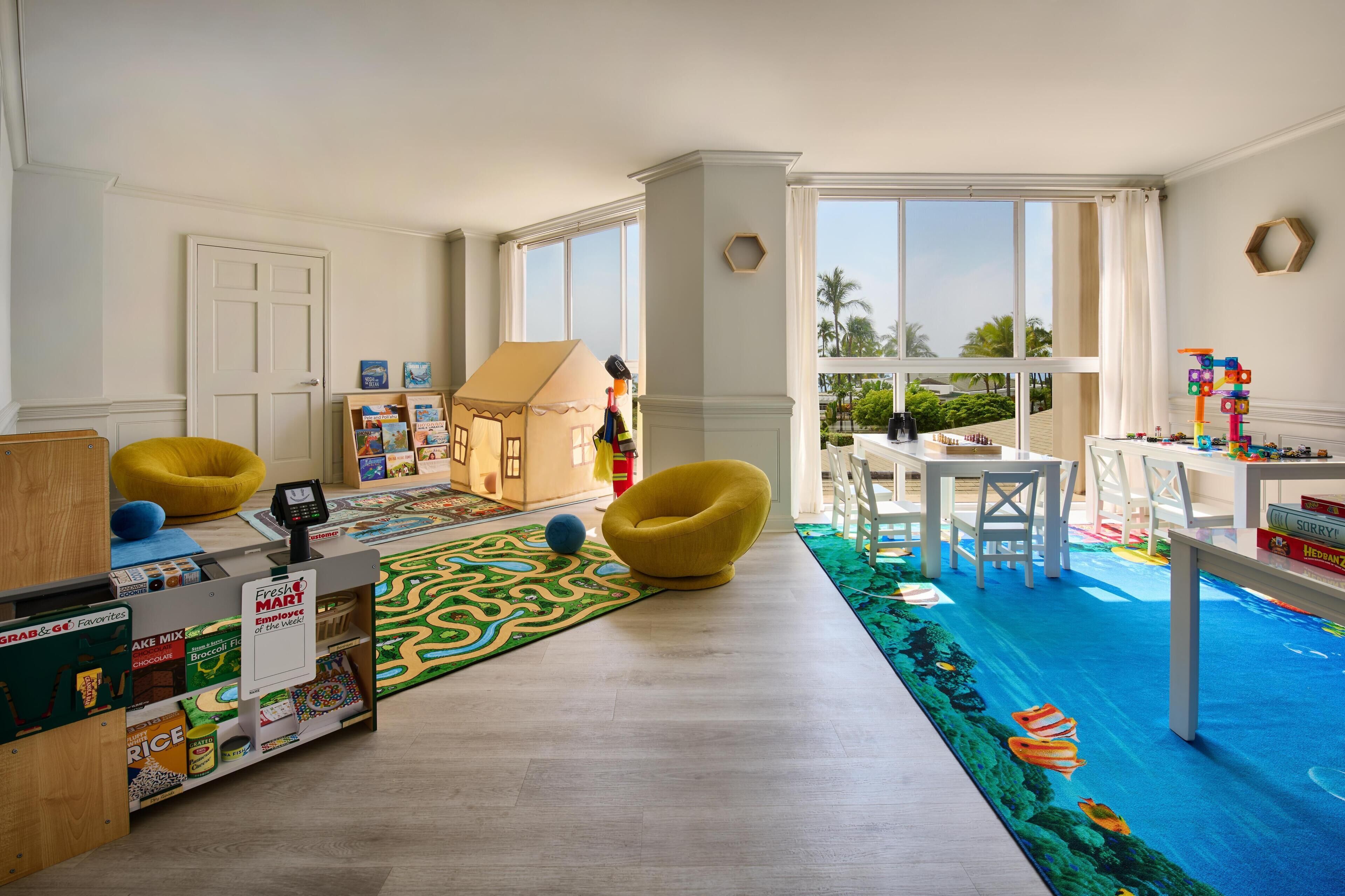 A children's play area with a playhouse, bean bag chairs, and a colorful play mat.
