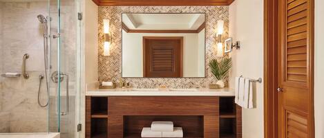 A modern bathroom with a glass shower enclosure, wooden vanity, and a large mirror.