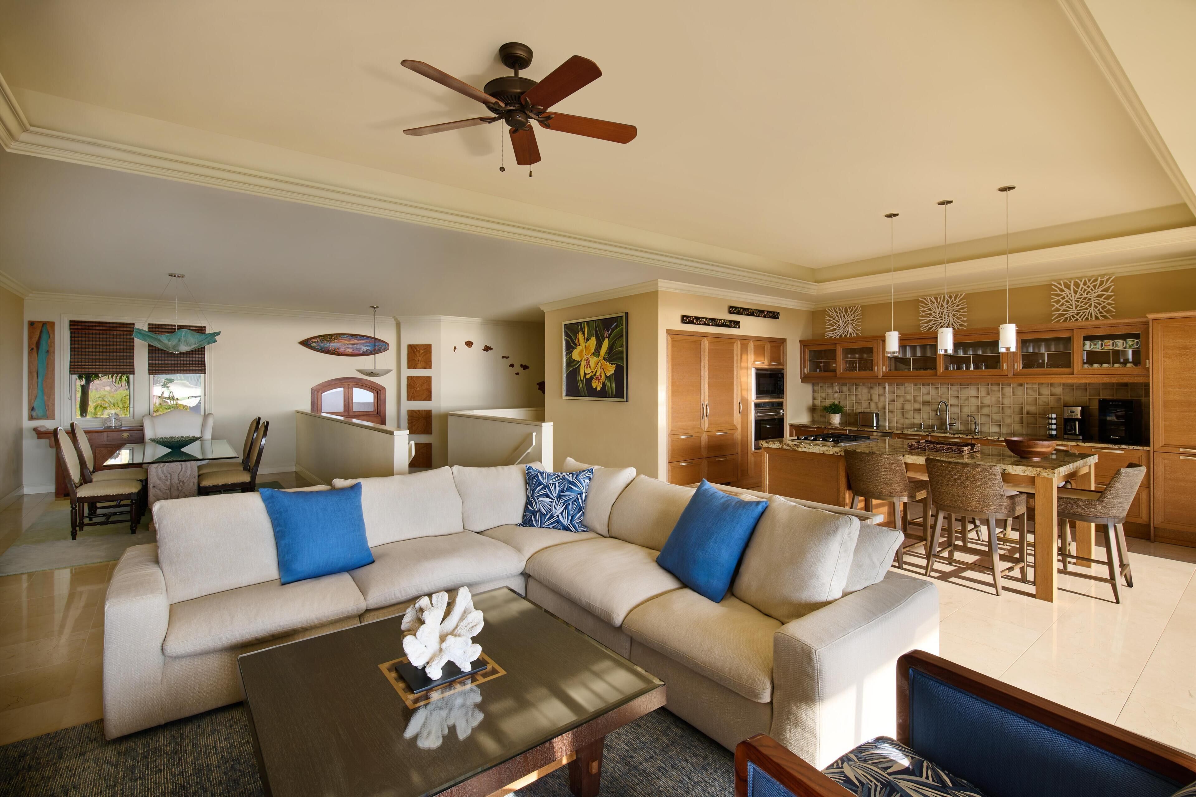 A living room with a sectional sofa, a coffee table, and a ceiling fan.