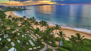 An aerial view of a beach resort with rows of sun loungers, palm trees, and a view of the ocean. - Grand Wailea Maui, A Waldorf Astoria Resort (Kihei)