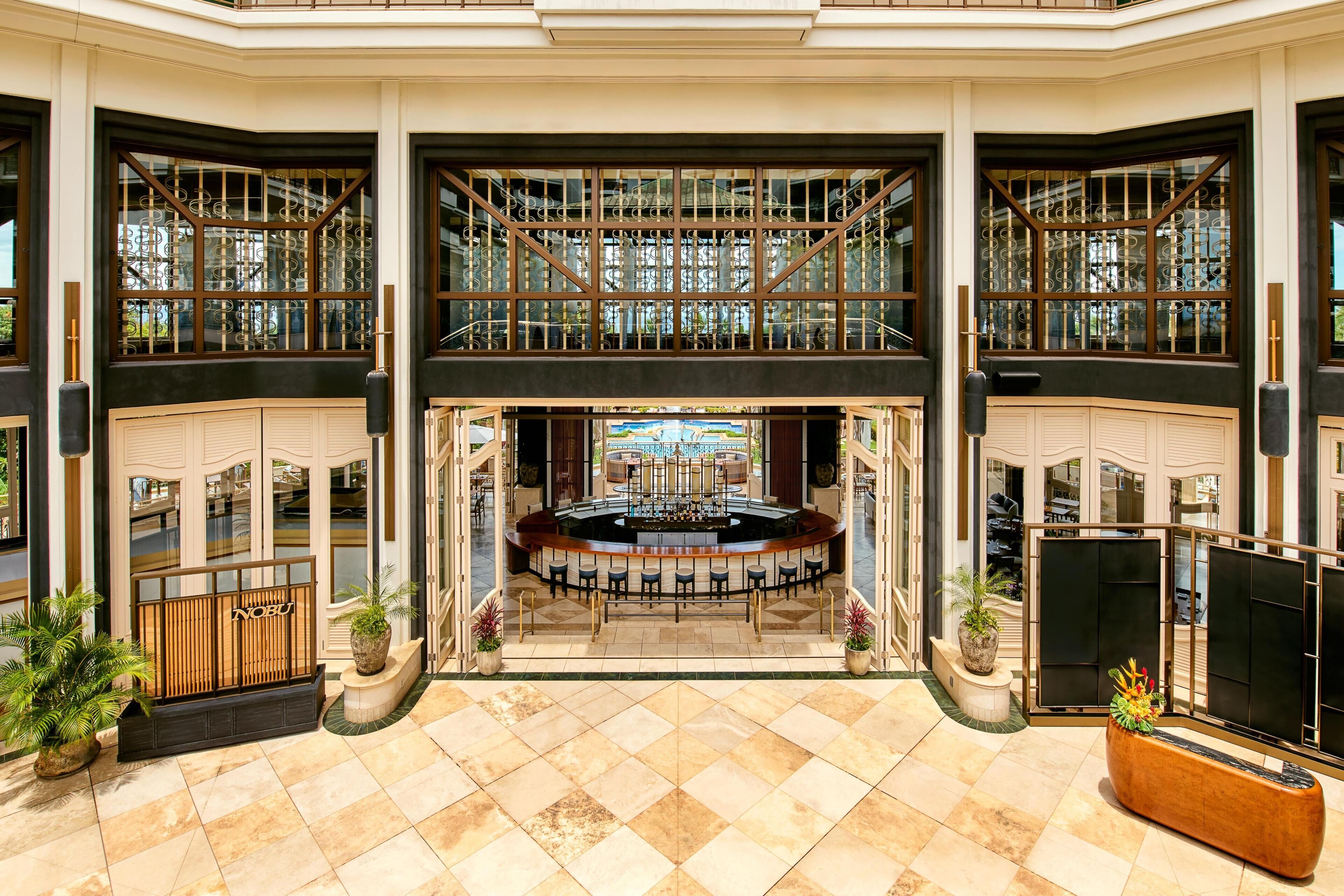 A spacious lobby with a central bar area, high ceilings, and large windows.