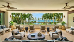 A spacious balcony with a view of a pool and palm trees, furnished with wicker chairs and a coffee table. - Grand Wailea Maui, A Waldorf Astoria Resort (Kihei)