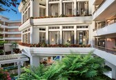 A multi-story hotel with balconies, indoor plants, and a pool area.