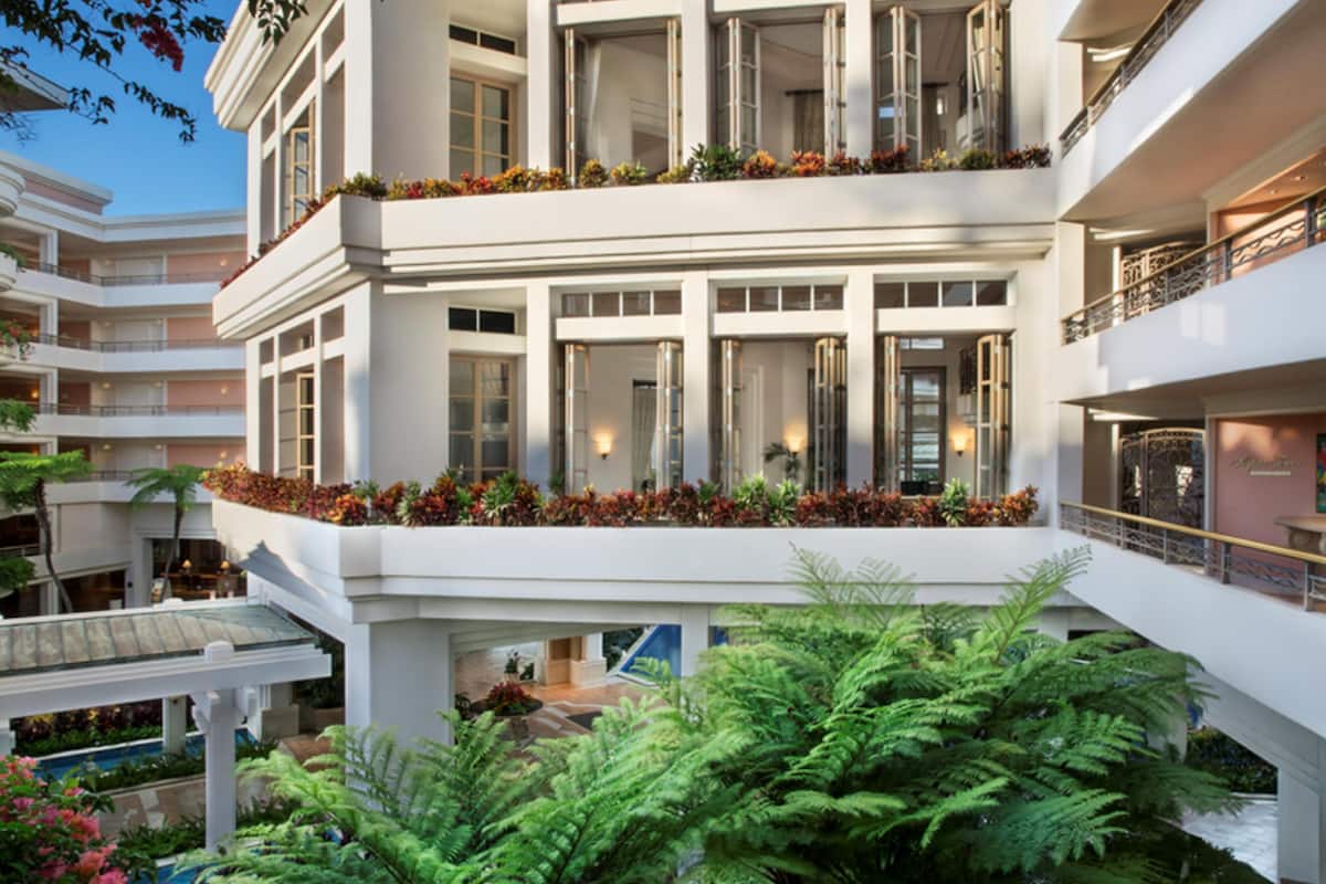 A multi-story hotel with balconies, indoor plants, and a pool area.