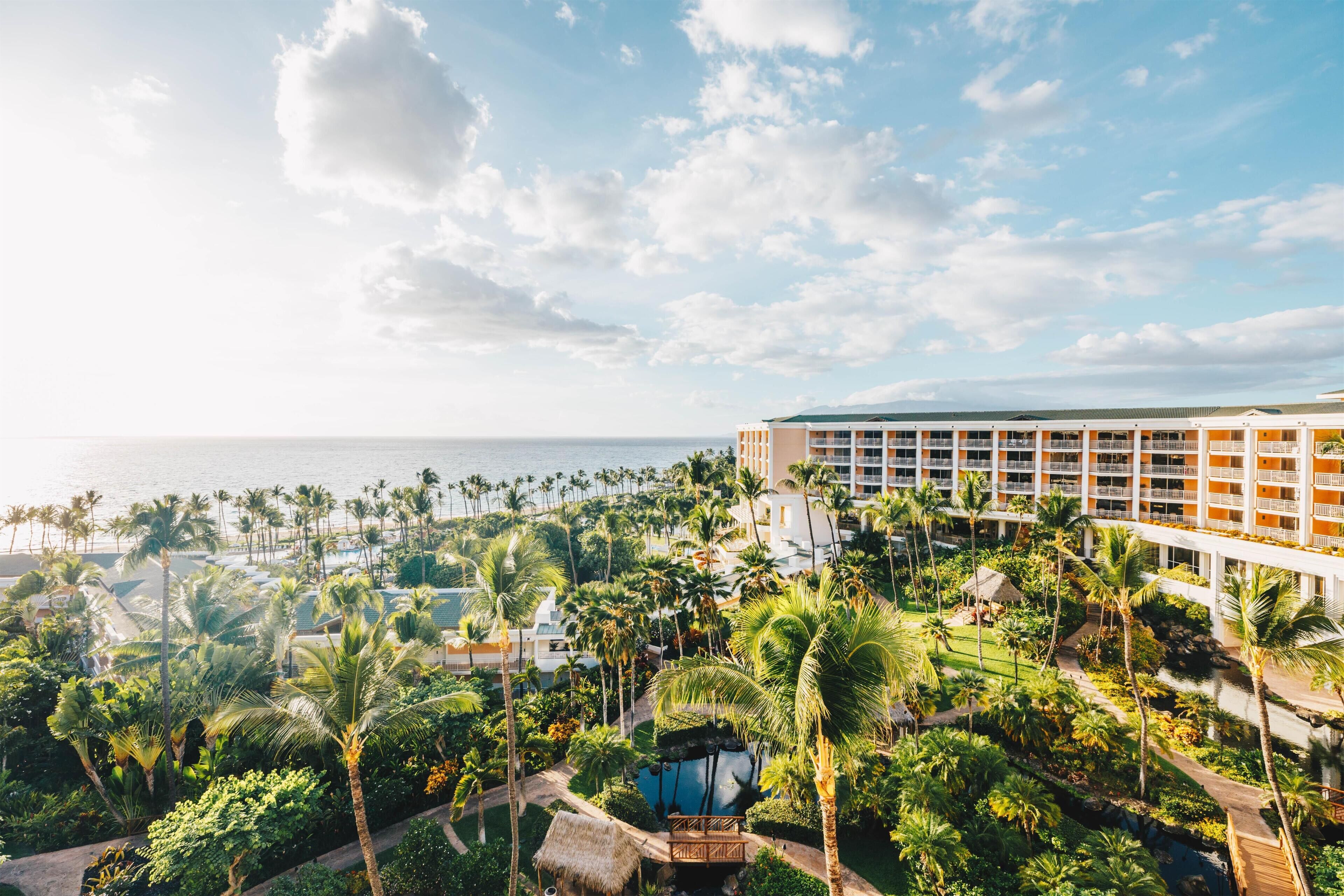 Een resort met een zwembad, palmbomen en uitzicht op de oceaan.