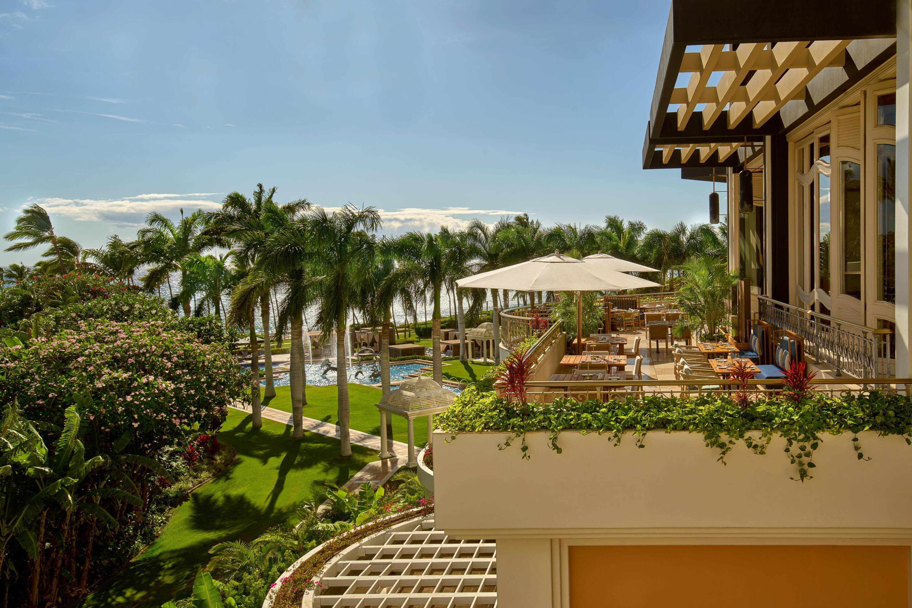 A resort with a pool, outdoor seating, and lush greenery.