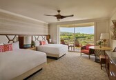 A hotel room with two beds, a ceiling fan, a balcony with a view, and a dining area.
