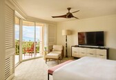 A hotel room with a bed, a television, a chair, a desk, and a balcony with a view.