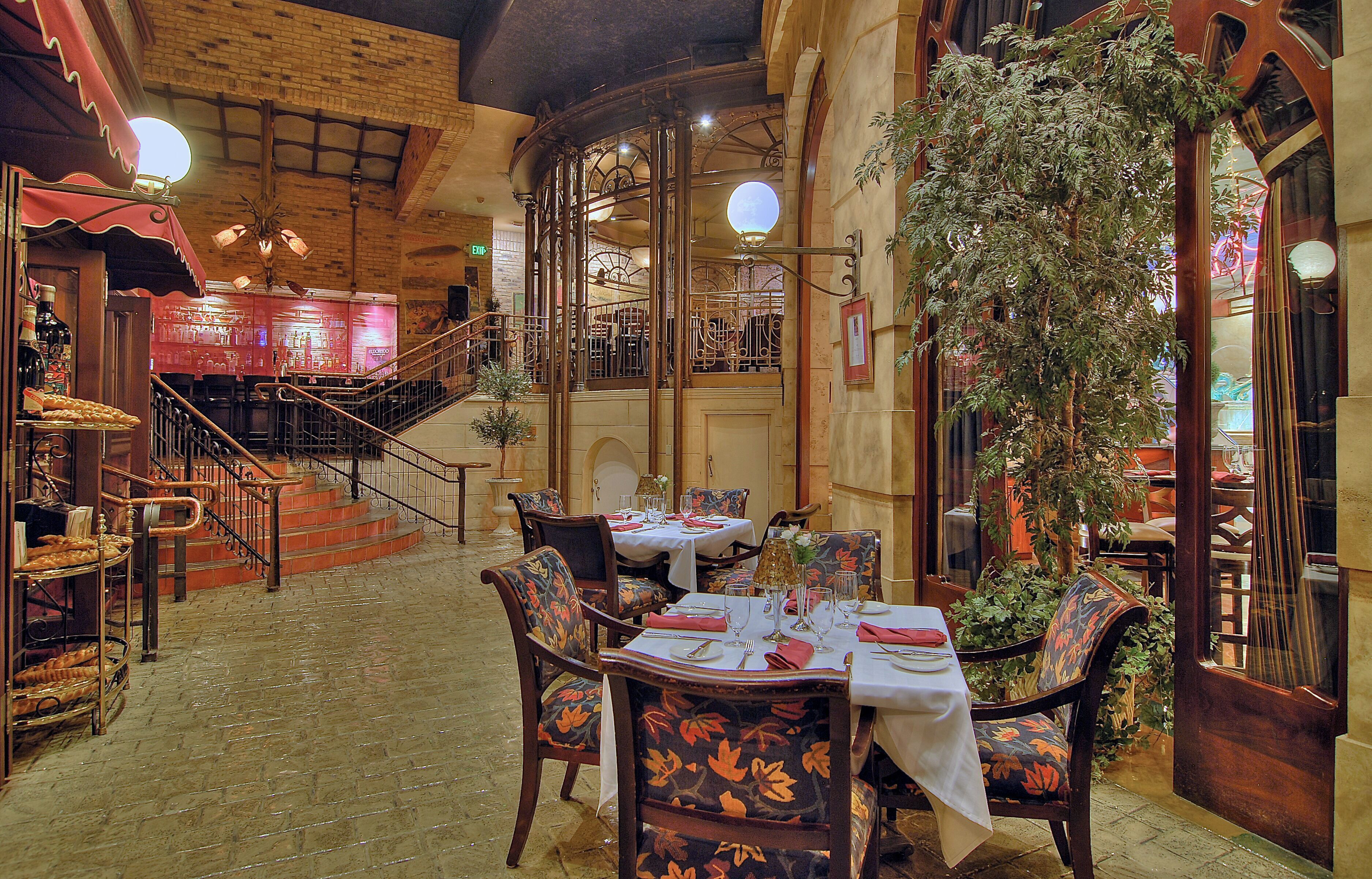 An indoor dining area with a brick ceiling, wooden staircase, and tables set for dining.