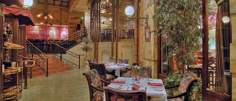 An indoor dining area with a brick ceiling, wooden staircase, and tables set for dining.