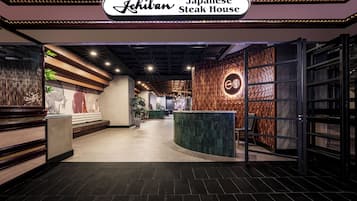 The entrance to a Japanese Steak House with a modern interior design, featuring a reception desk, seating area, and decorative elements.