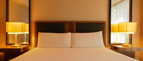 Una habitación de hotel con una cama grande, dos mesitas de noche y dos lámparas.
