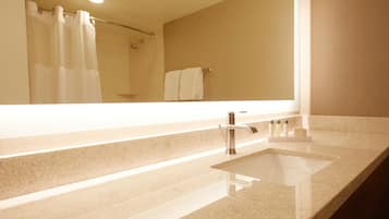 A bathroom with a large mirror, a sink, and a shower area.