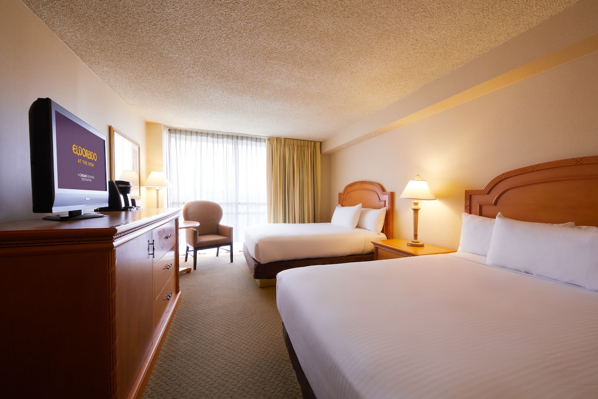 A hotel room with two beds, a TV, a desk, and a chair.