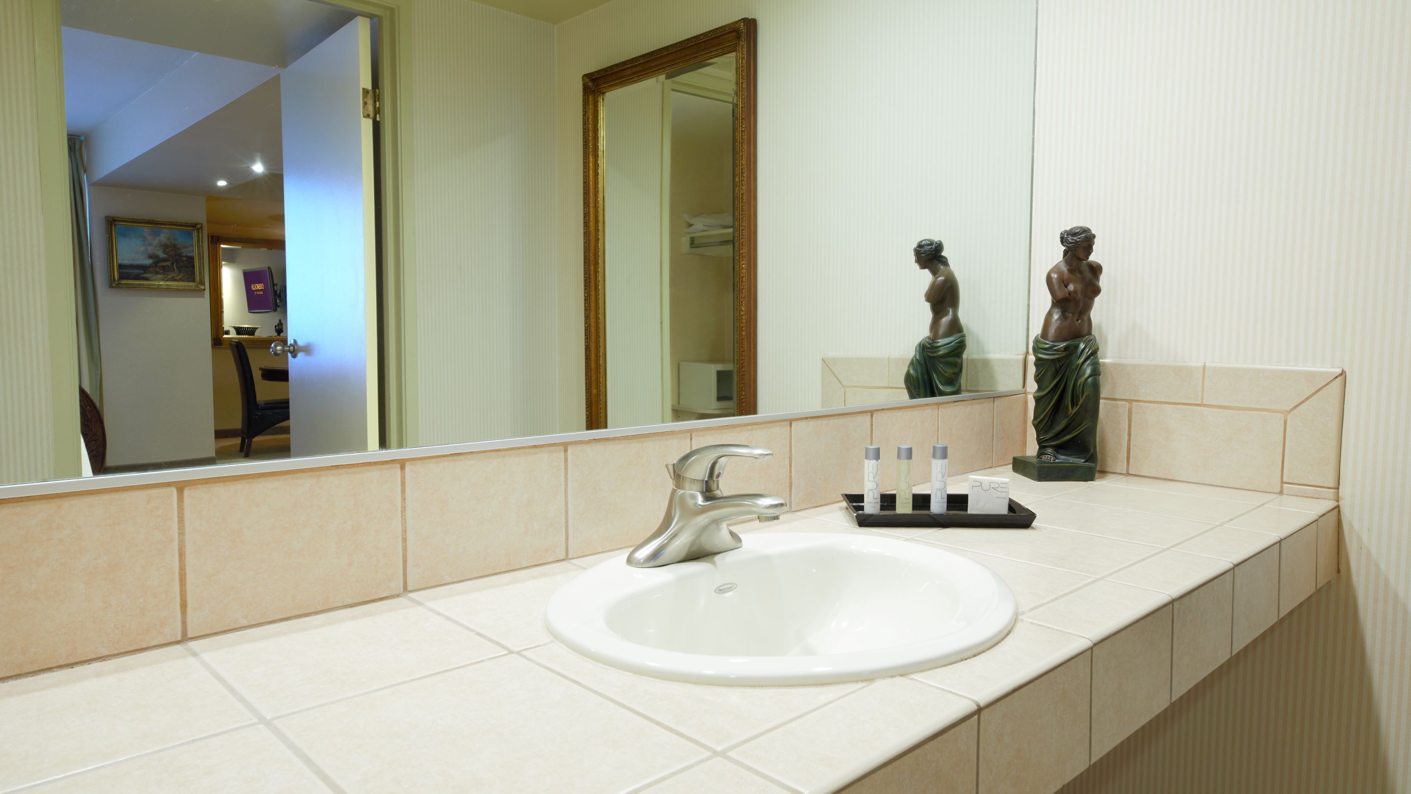 A bathroom with a white sink, a mirror, and a statue.