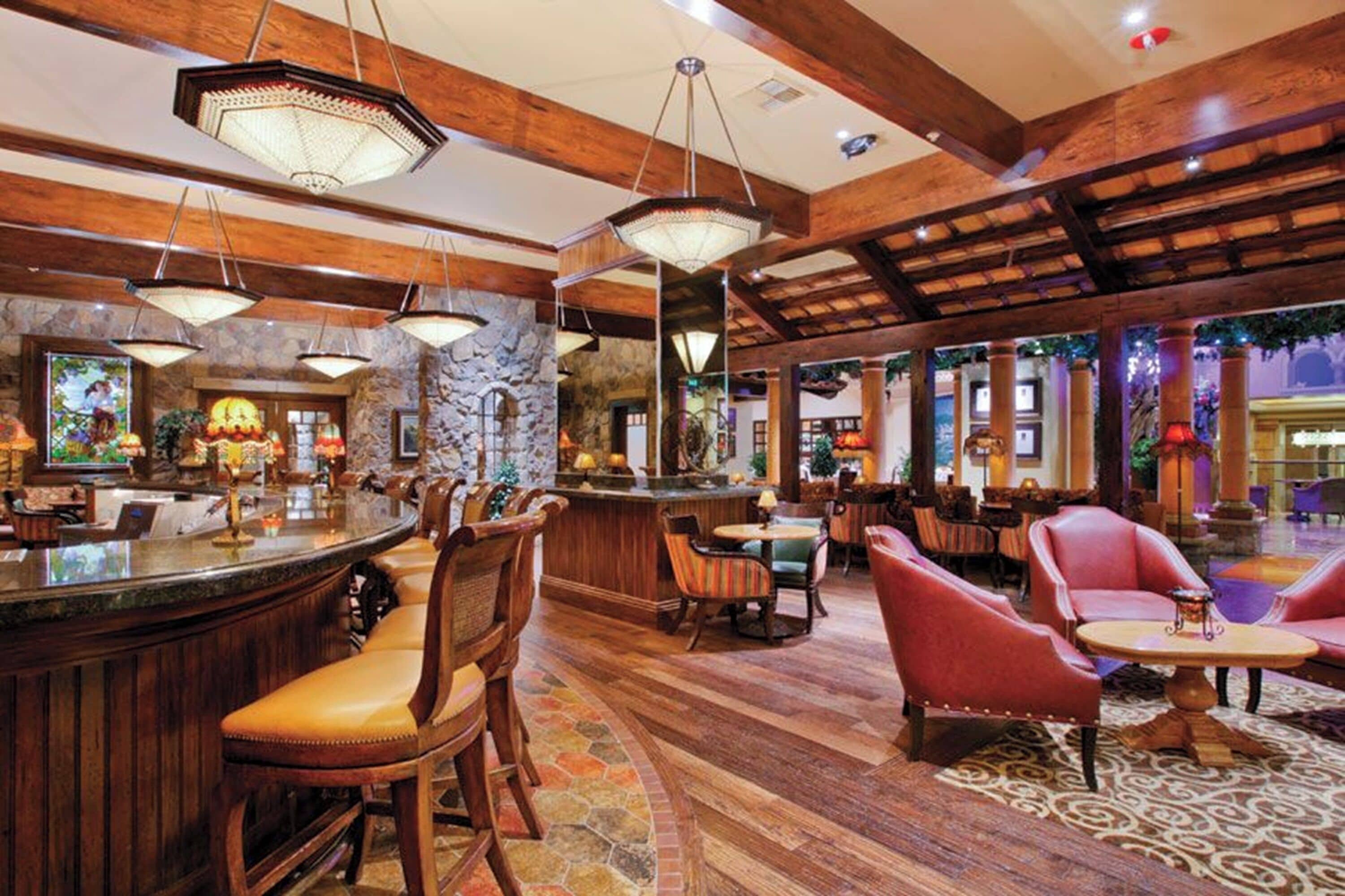 Un vestíbulo amplio con una zona de bar, asientos y un techo decorativo.