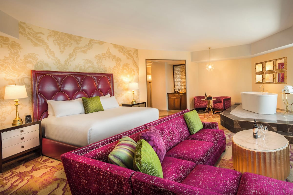 A hotel room with a large bed, a sofa, a round table, and a TV.