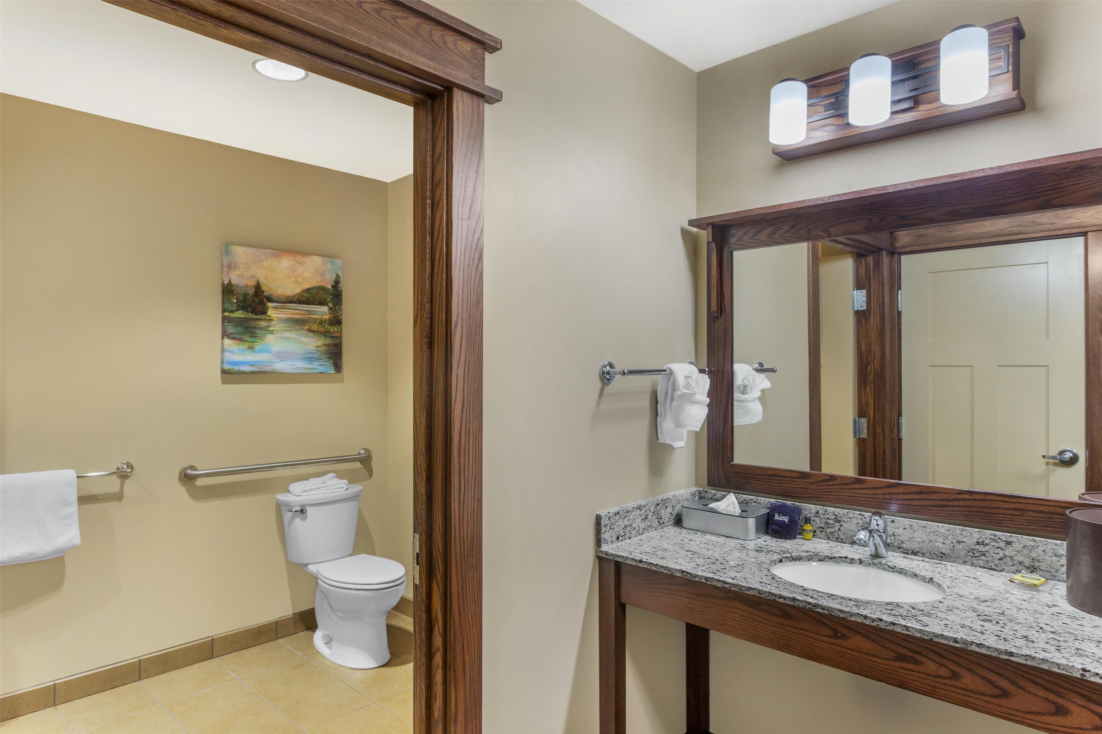 A bathroom with a toilet, sink, and a painting on the wall.