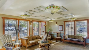 A cozy lobby with a wooden bench, a sofa, and a table with a vase. There are large windows and a ceiling with geometric patterns. - Best Western Plus High Country Inn (Ogden)