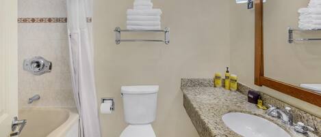 Une salle de bain équipée d’une baignoire, de toilettes, d’un lavabo et de porte-serviettes.