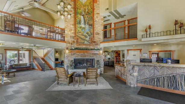 A spacious lobby with a stone fireplace, wooden furniture, and a high ceiling with exposed beams. - Best Western Plus High Country Inn (Ogden)