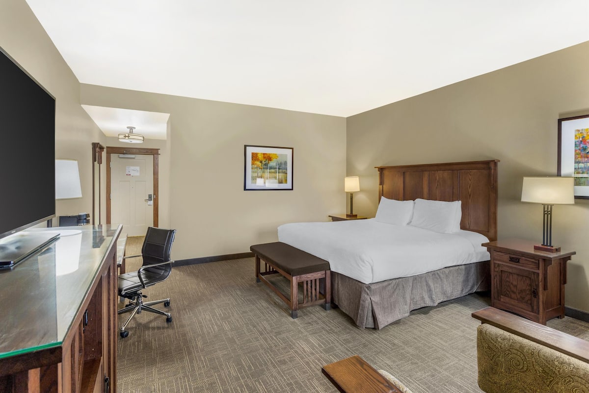 A hotel room with a bed, desk, chair, and a television.